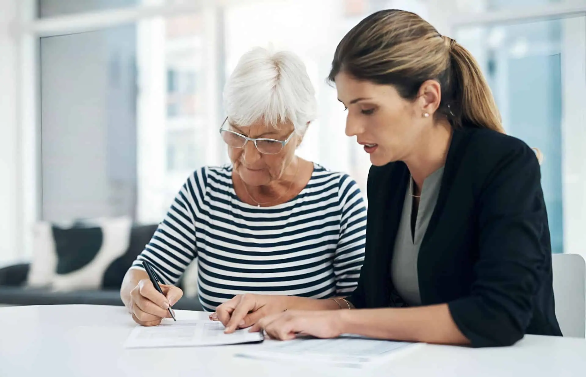 A woman helping an older woman fill out a form