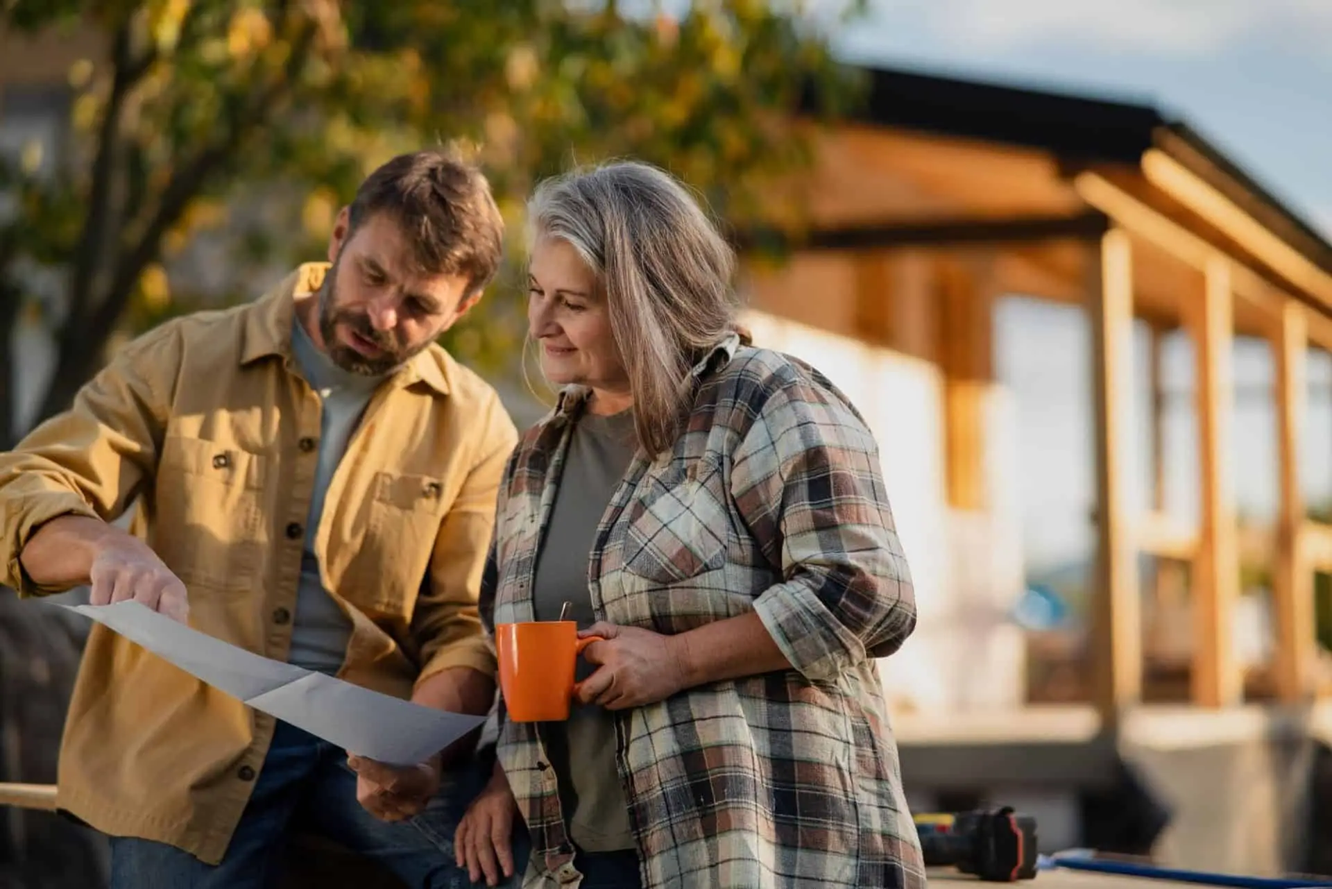 A man and an older woman reading a document outside a house