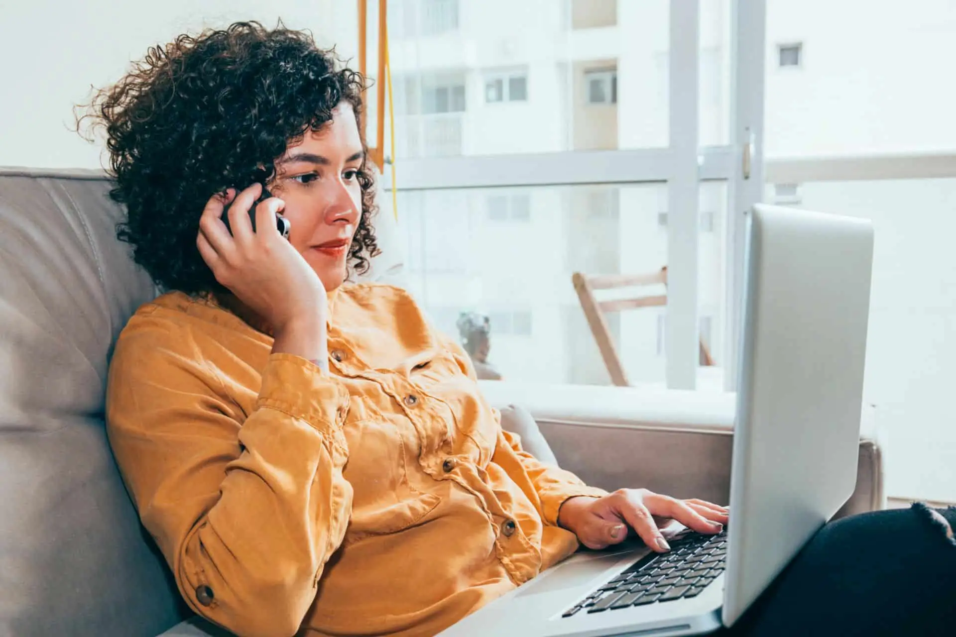 A woman on a phone call while working on a laptop