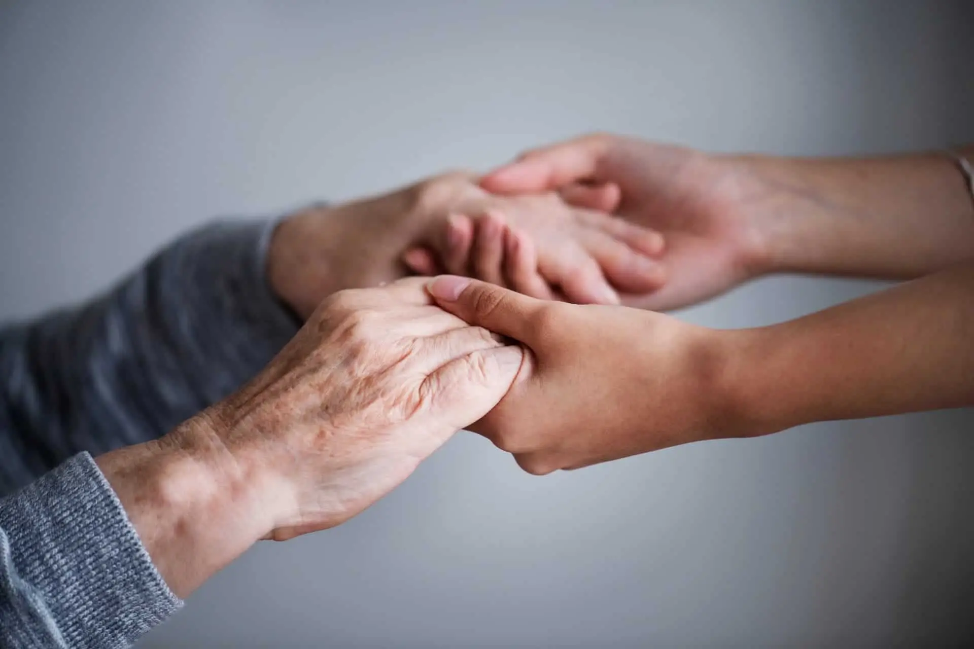 An older person's hands held in a younger person's hands